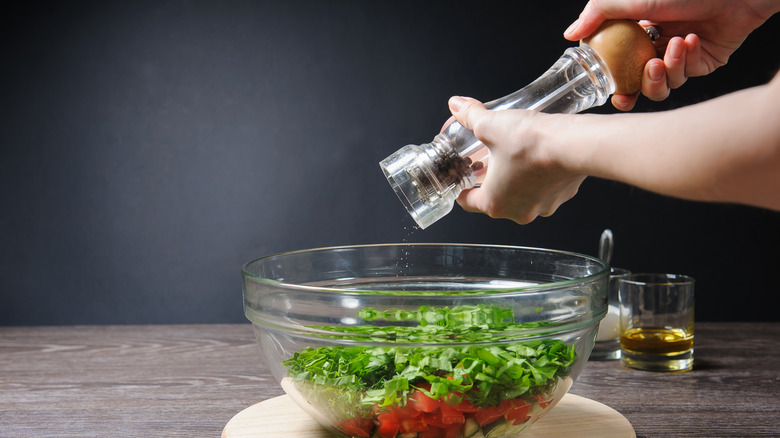 adding pepper to salad