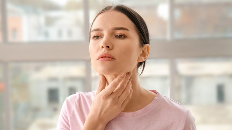 woman touching thyroid area