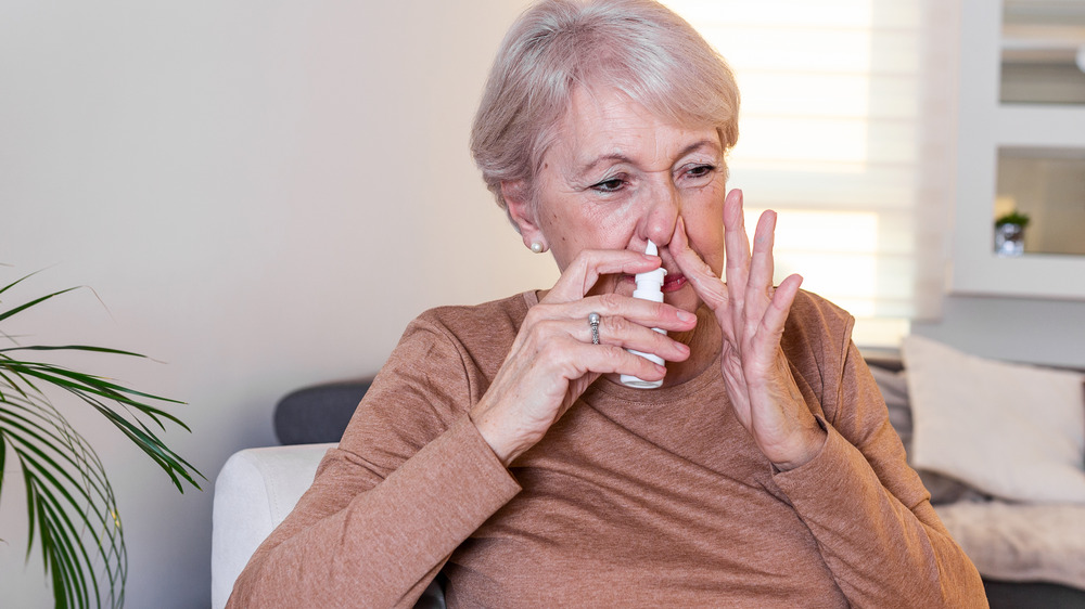 Woman using nose spray 