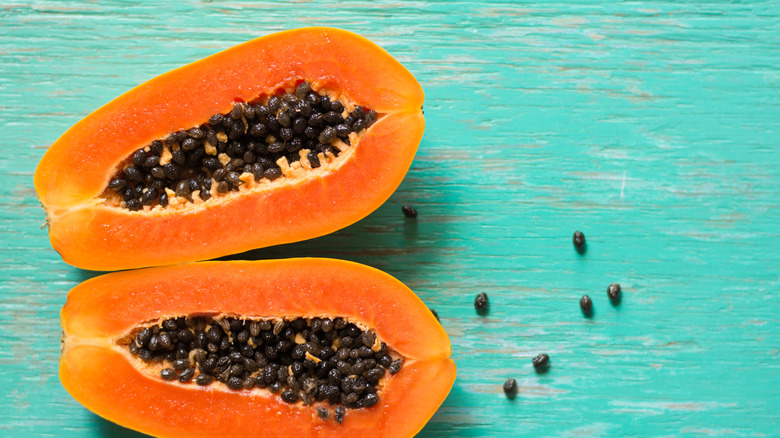 Two papaya halves on a wooden table