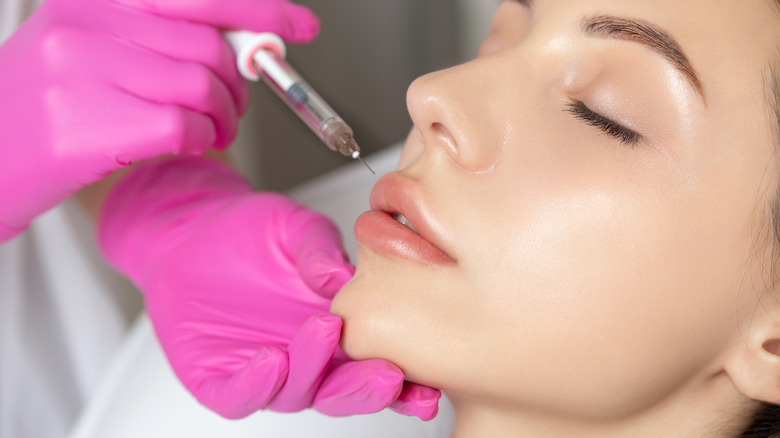 pink gloves injecting lip fillers on a young woman