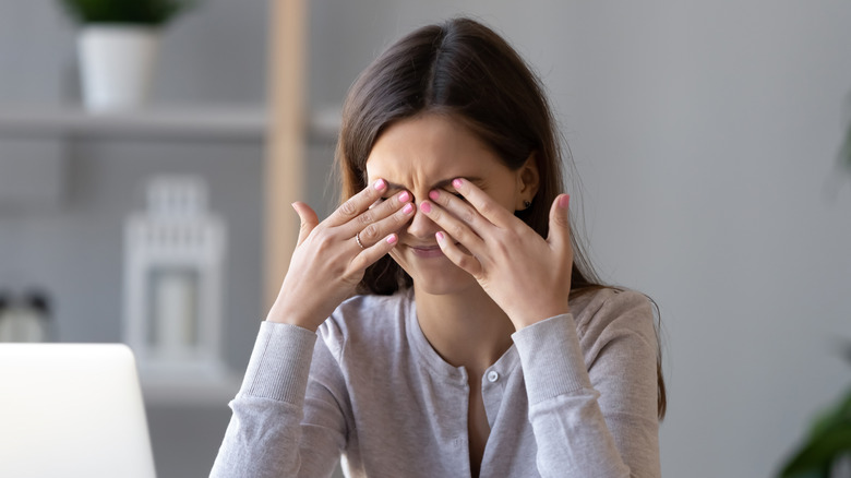 Woman rubbing eyes and squinting