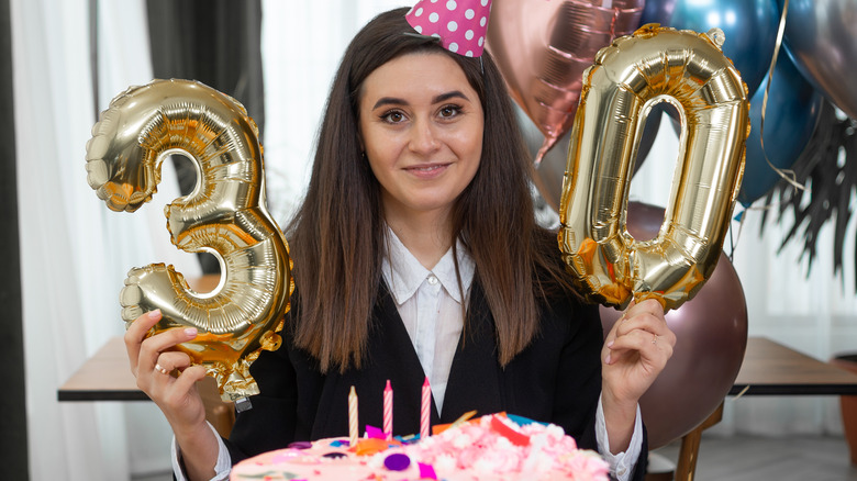 Woman holding 3 and 0 balloons