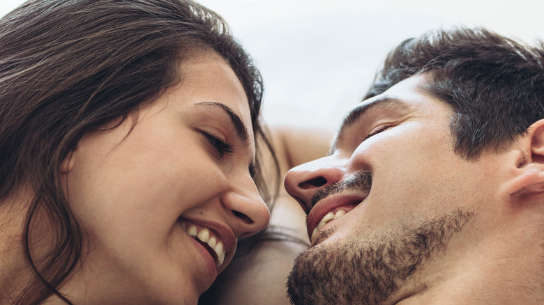 Couple laying in bed romantically staring 