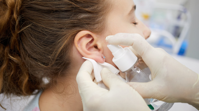 Pierced ear being sterilized