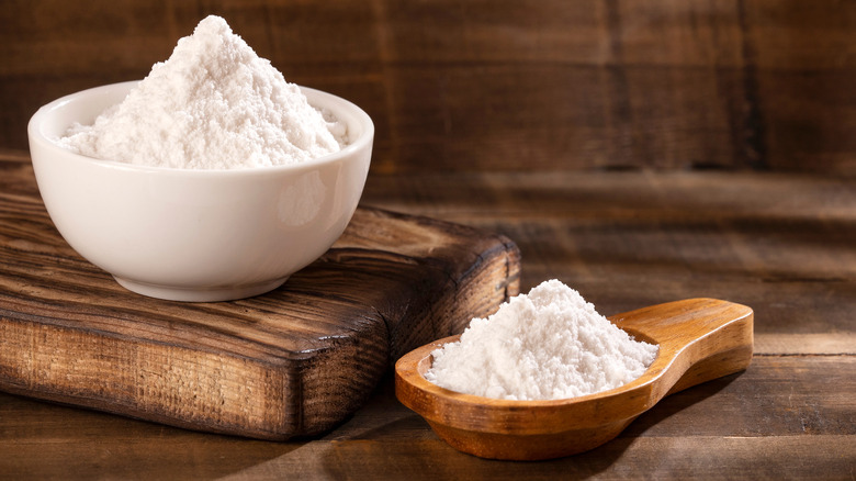 A bowl and spoonful of baking soda on a kitchen counter