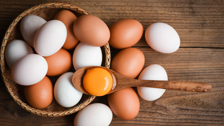 Brown and white eggs surrounding raw egg in a spoon