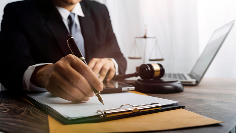 Judge with gavel and writing on legal document
