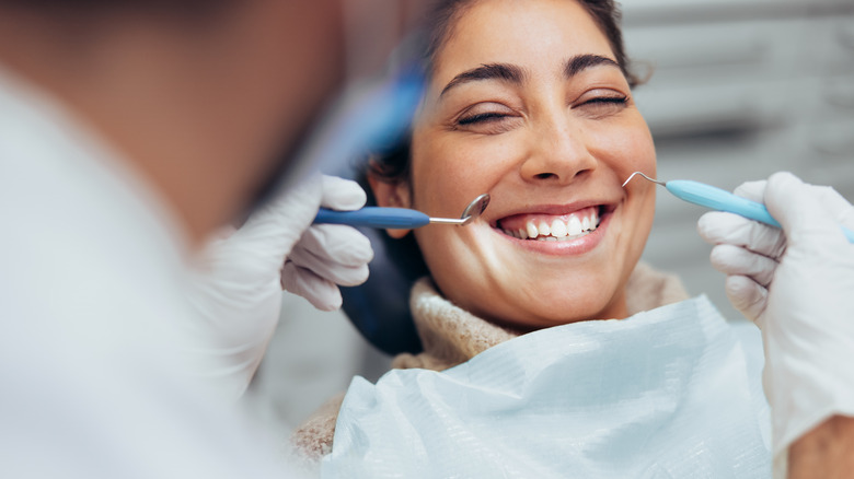 Dentist examines smiling woman's teeth
