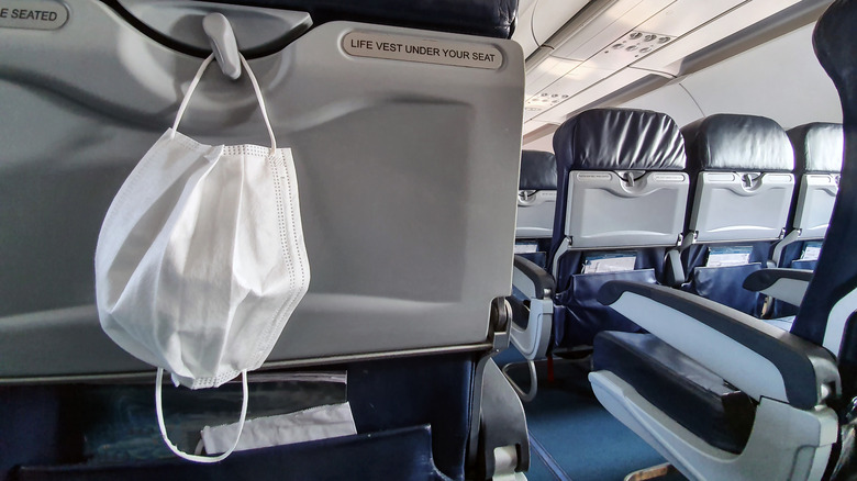 Mask hanging on the back of airplane seat on empty airplane