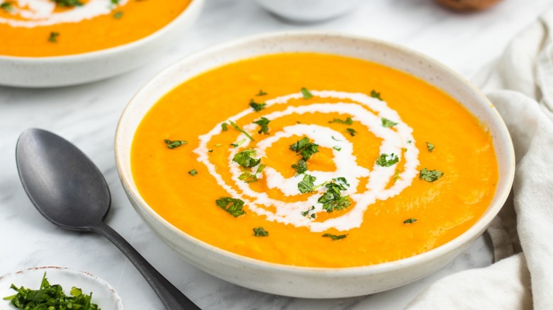 Sweet potato and carrot soup, swirled with cream and sprinkled with parsley