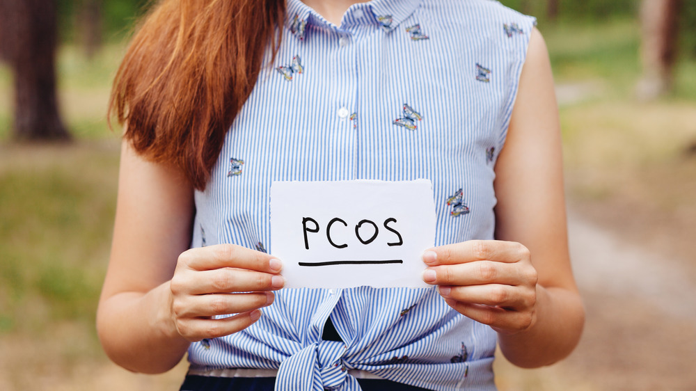 PCOS written on paper held up by woman