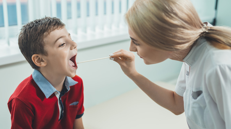 Doctor checking young boy's throat for strep