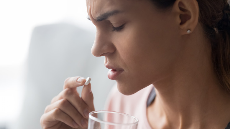 Unhappy woman taking pill