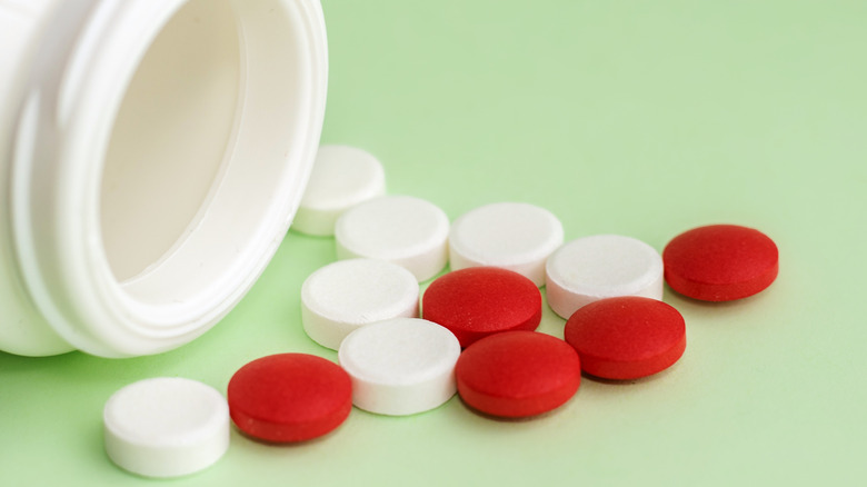 a toppled over bottle of ibuprofen and aspirin