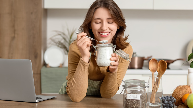 young woman eating yogurt at counter with chia seeds