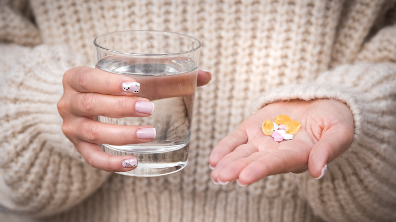 A woman holds a handful of supplements