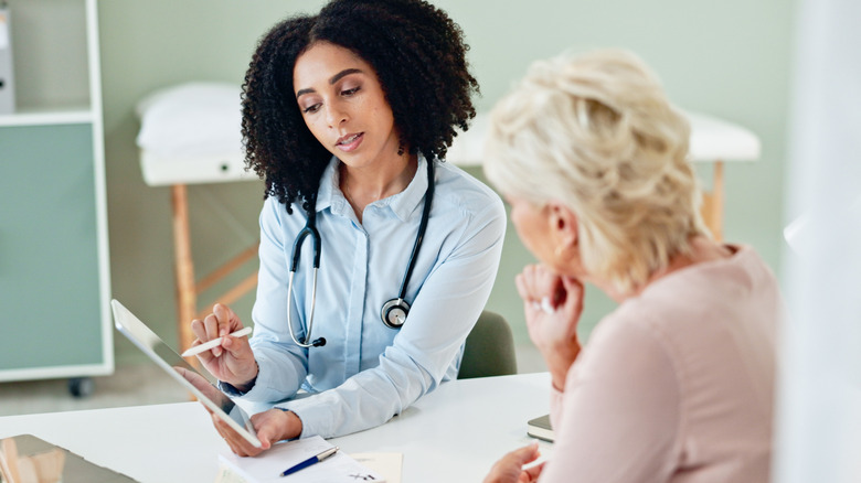 A doctor pointing to a digital tablet while talking to a female patient