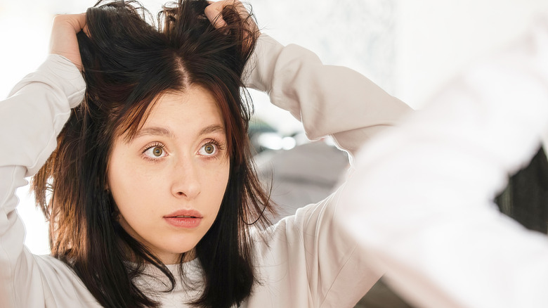 young woman surprised by her hair in the mirror