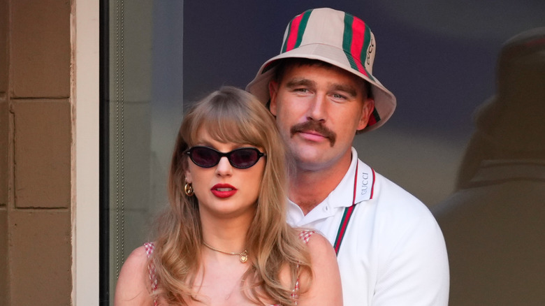 Travis Kelce standing behind Taylor Swift