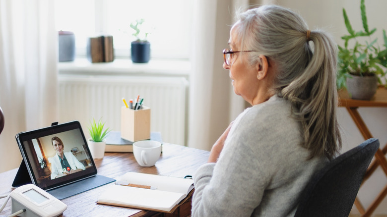 A senior using a tablet to video chat with her doctor