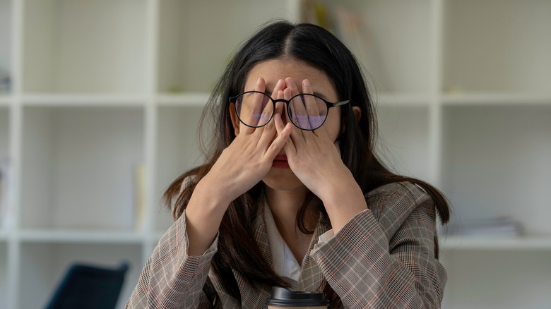 woman with headache rubbing her eyes