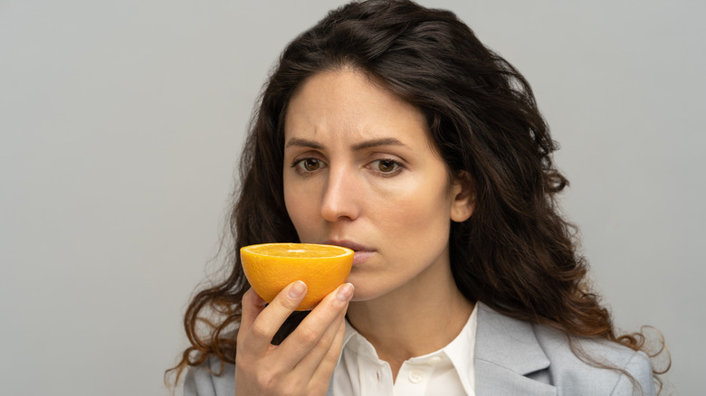 A woman tries to smell an orange