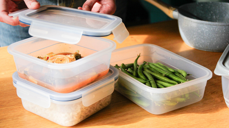 Man storing leftovers in plastic containers