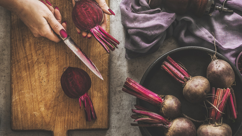 A woman preparing beets on a cutting board
