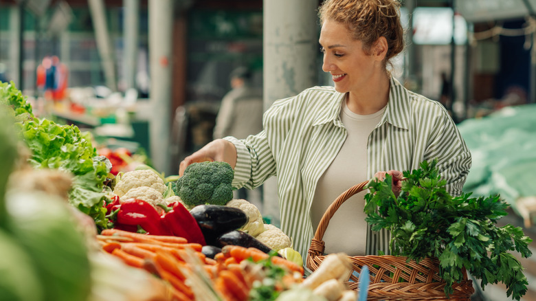 A woman at the supermarket picking up some broccoli