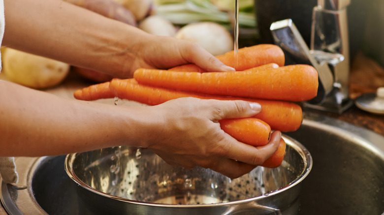 A woman rinsing carrots in the sink