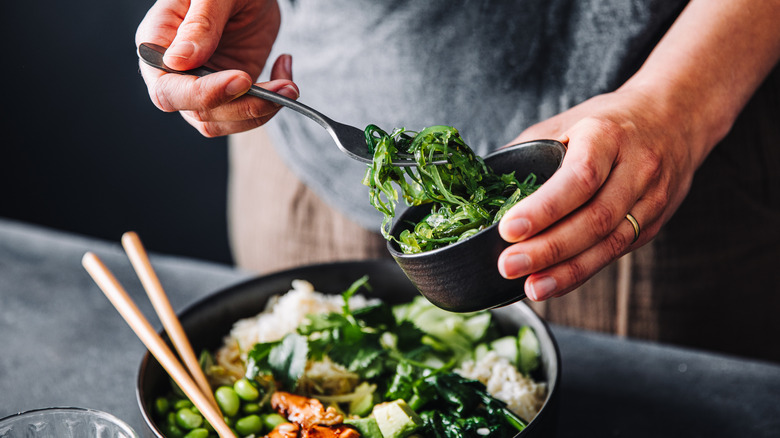 A woman putting spinach into a salad