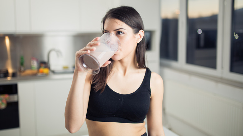 woman drinking a whey protein shake in her kitchen