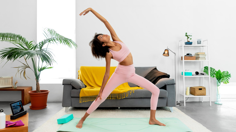 woman doing reverse warrior pose in her living room