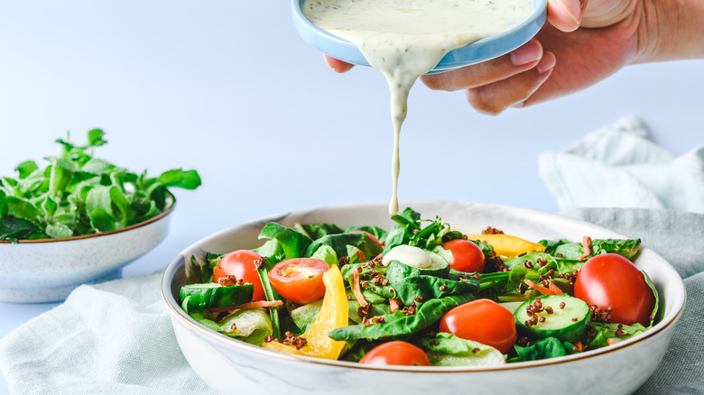 person pouring dressing on salad