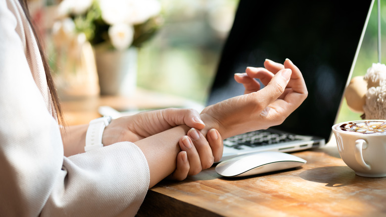 Someone holds their wrist near a computer