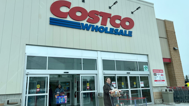 A woman going out of Costco with a shopping cart
