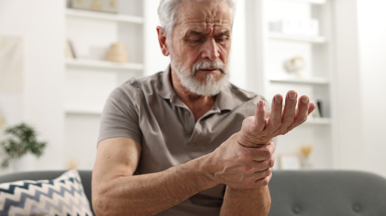 mature man holding wrist at home