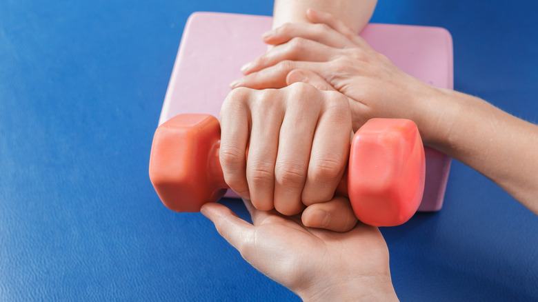 hand holding pink dumbbell on table