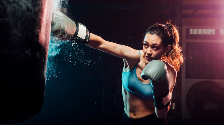 Woman boxing and hitting punching bag