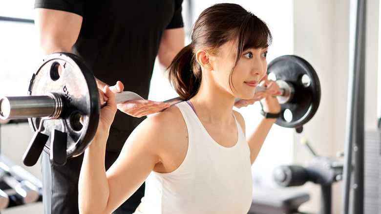 Young woman doing barbell back squats