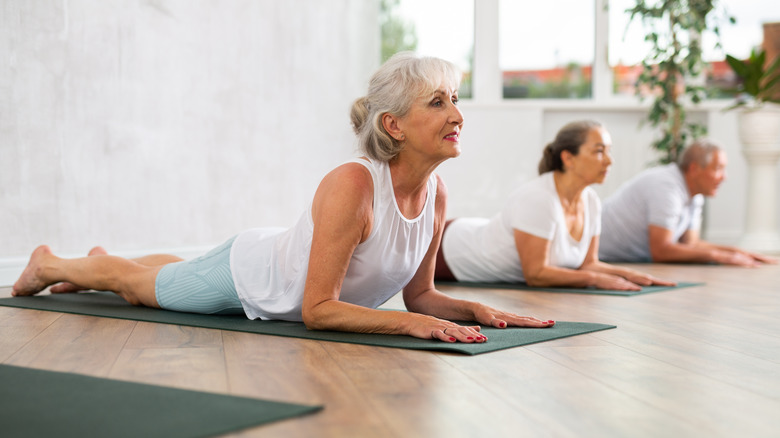 A class of senior yoga students doing cobra pose on yoga mats