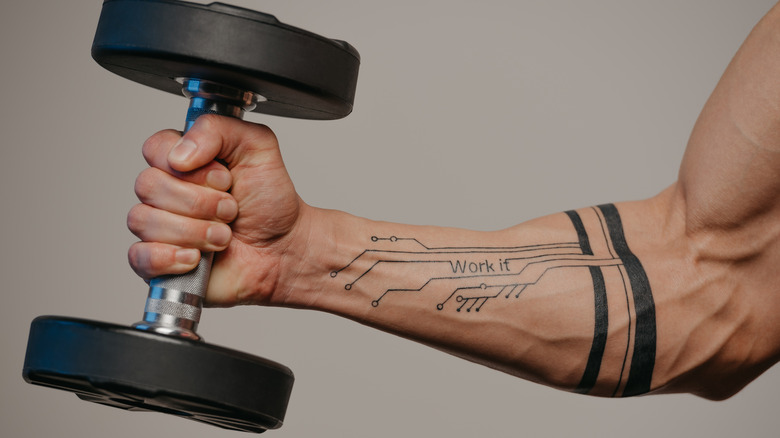 tattooed forearm holding dumbbell