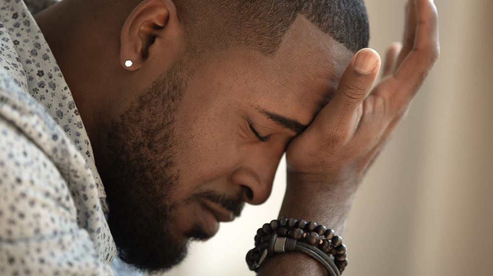 close-up of a man resting his brow on the heel of his hand