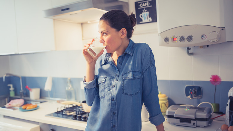 Woman drinking milk in kitchen