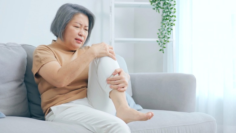 Older Asian woman holds painful knee