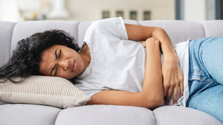 woman lying on couch, stomach pain