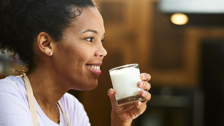 woman drinking a small glass of milk