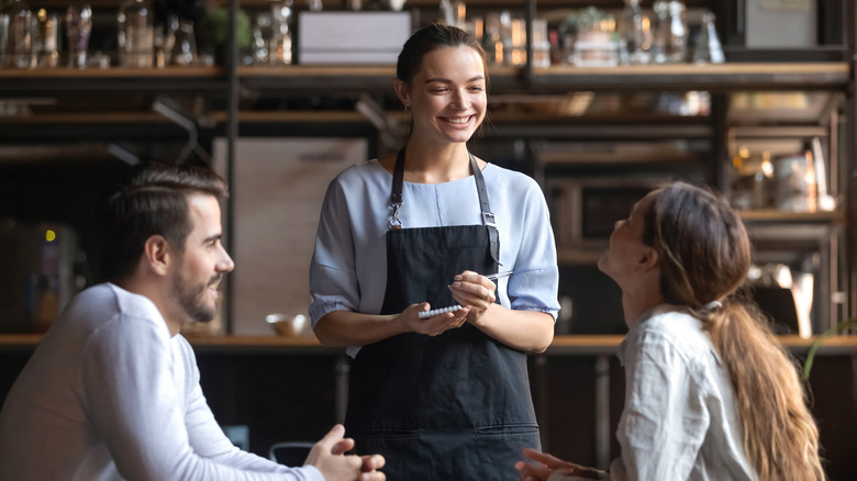 two hungry restaurant patrons giving their lunch order to a server 