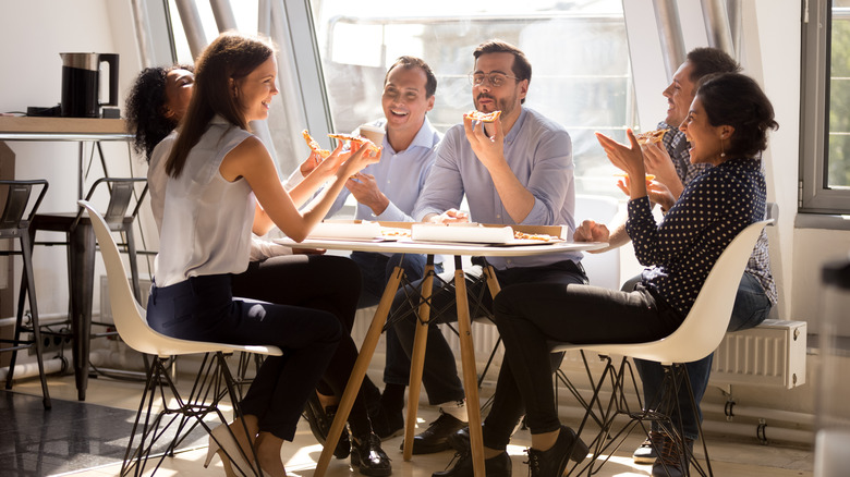 Happy co-workers sharing a pizza